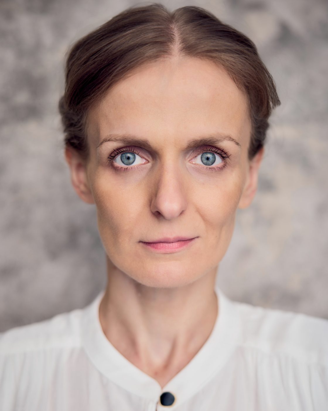 Monika Valkunaite headshot, white shirt, hair pulled back